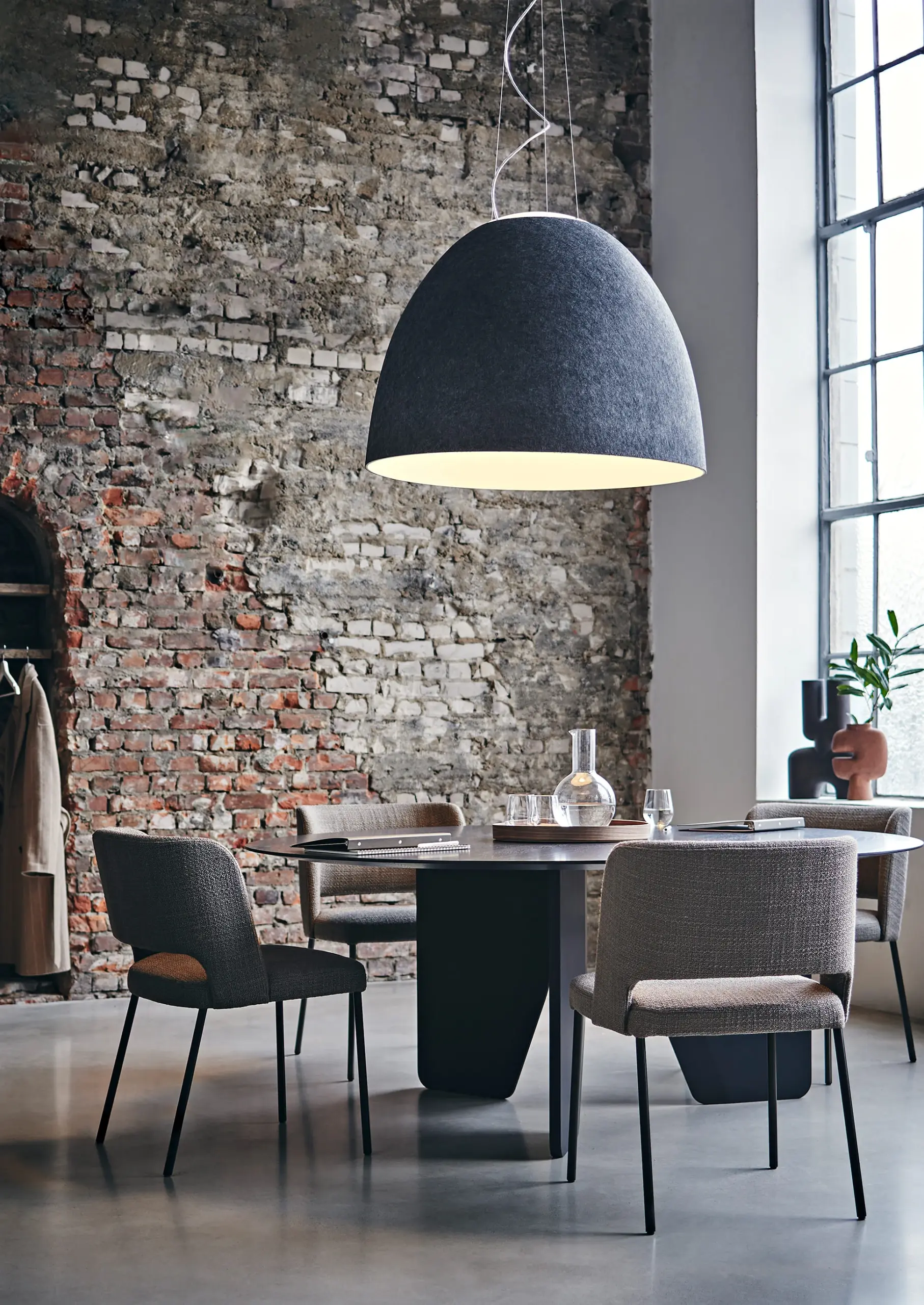 Artemide Pendelleuchte Nur Acoustic mit schallabsorbierendem Schirm über einem runden Esstisch