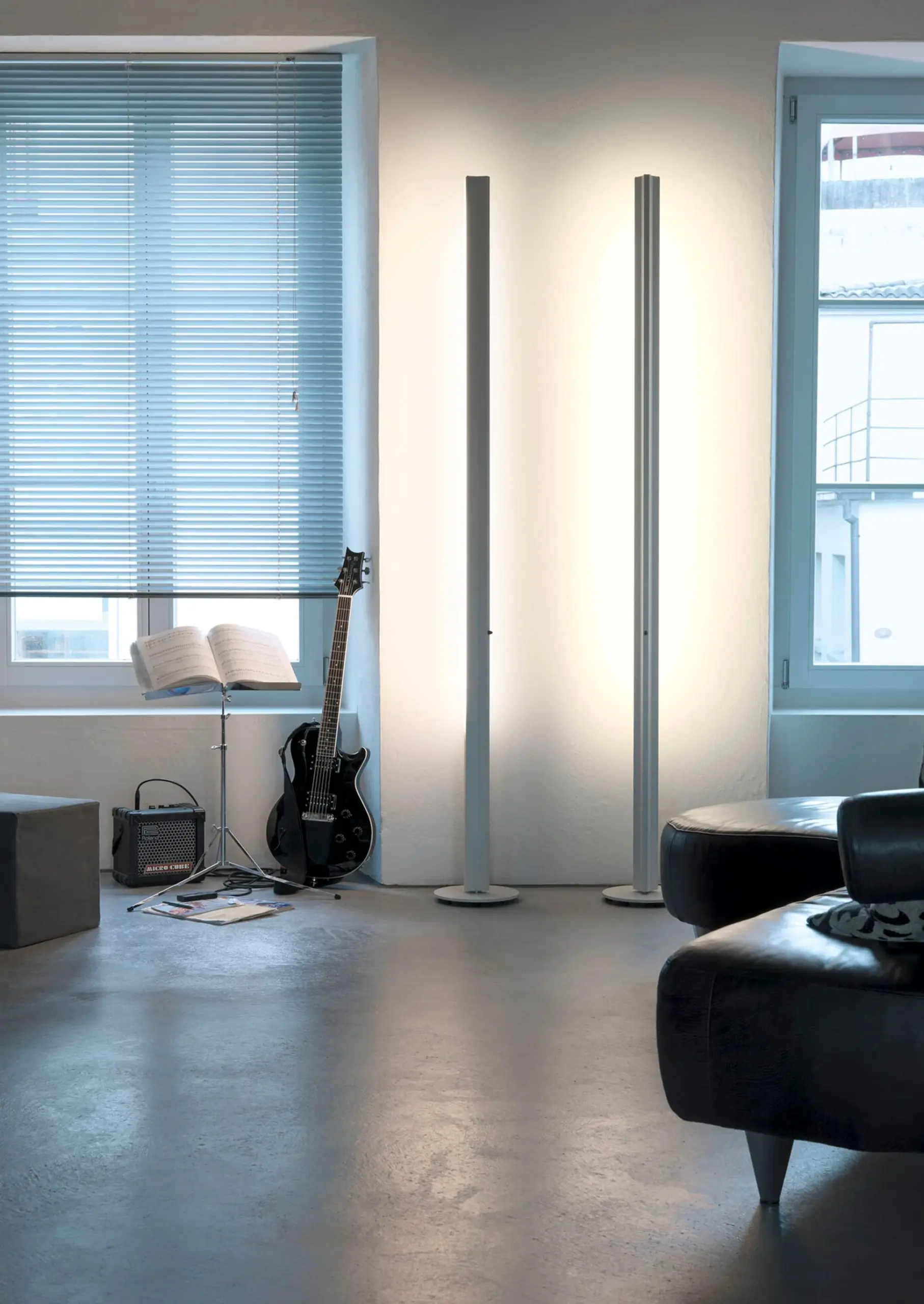 Zwei schlanke Belux Stehlampen Ypsilon als Lichtsäulen im Wohnzimmer