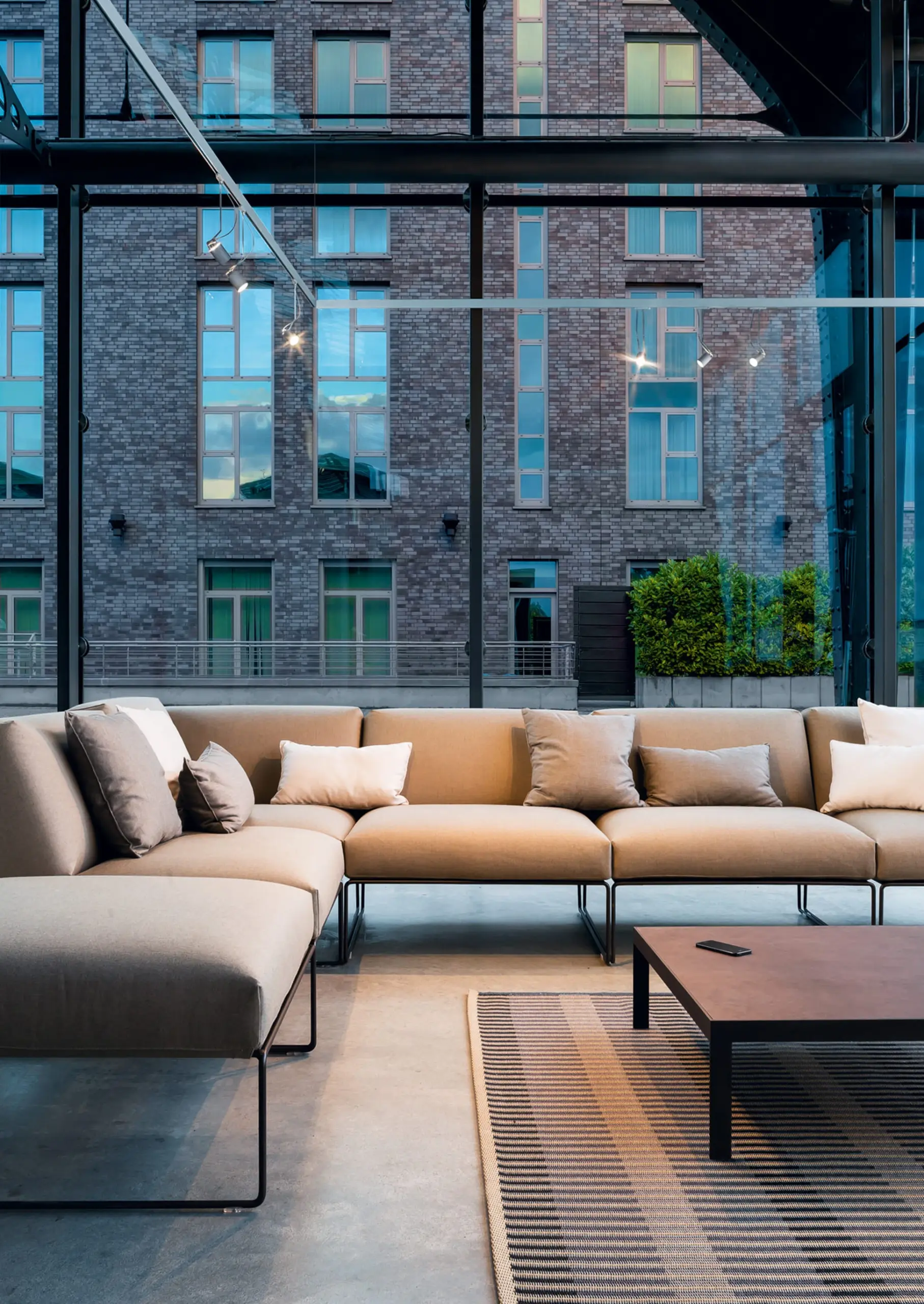Buschfeld Lichtsystem Flex mit Strahlern über einer Sofaecke vor einer Glasfassade