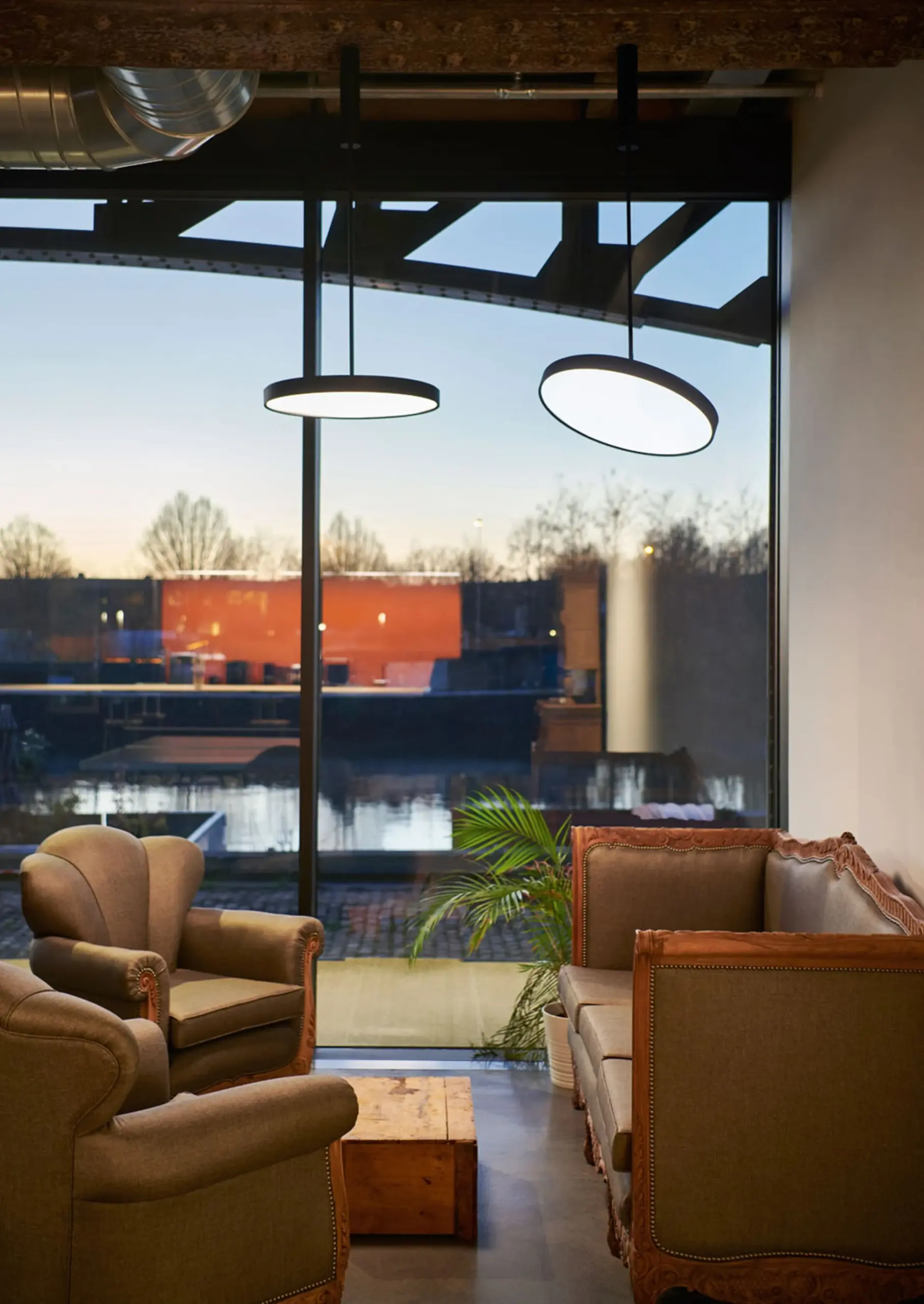 Zwei runde Delta Light Pendelleuchten Multinova in einer Lounge am Wasser