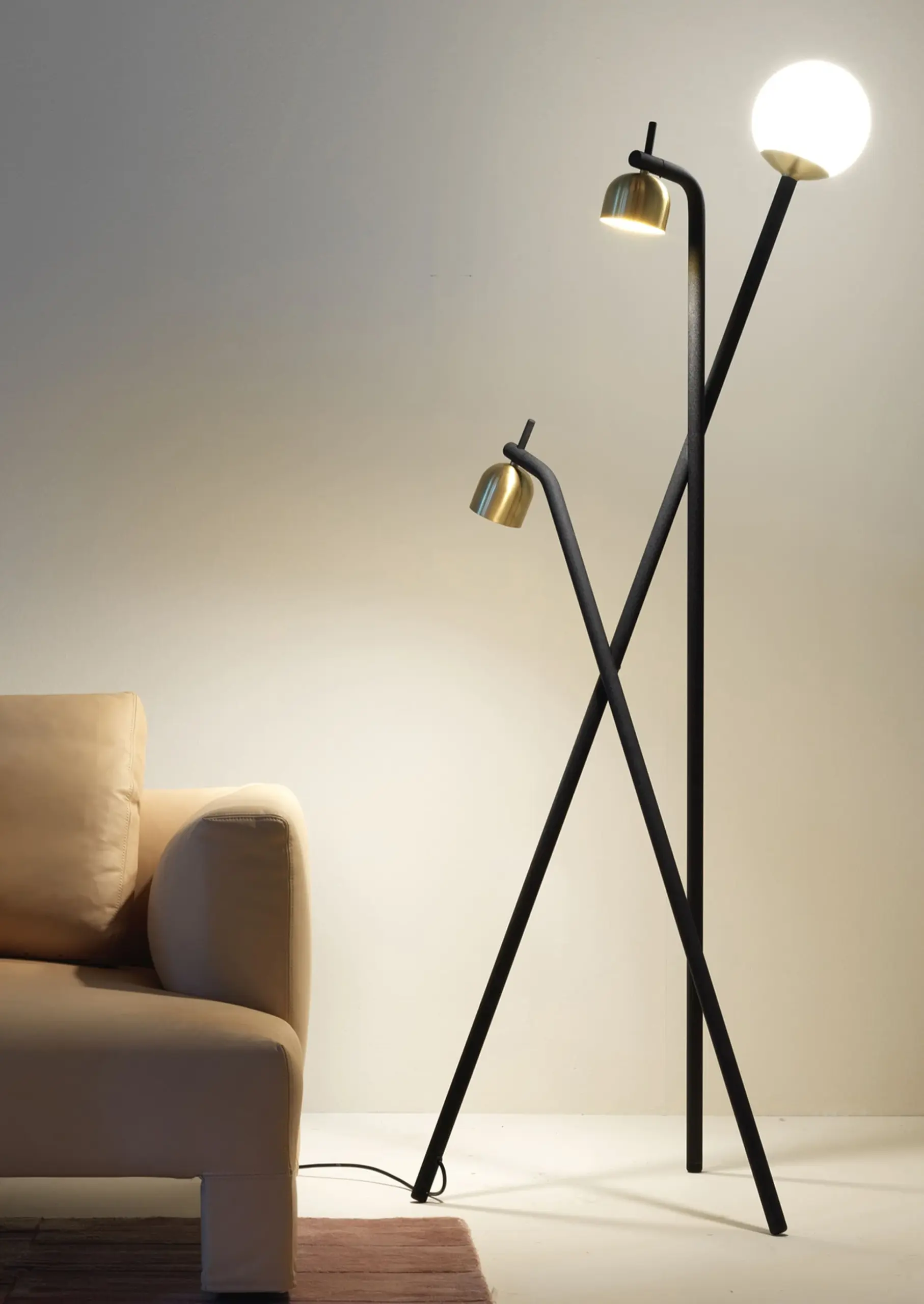 FontanaArte Stehlampe Tripod mit Messingschirmen und Glaskugel neben hellem Sofa