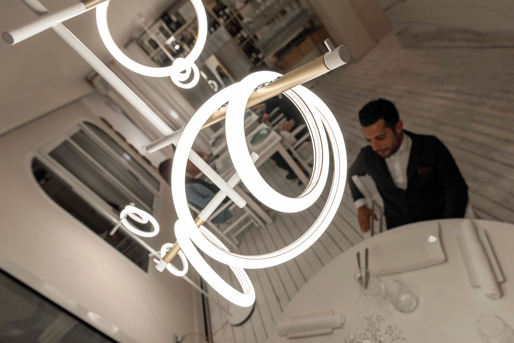Marchetti Pendelleuchten mit leuchtenden LED-Ringen über den Tischen eines Restaurants