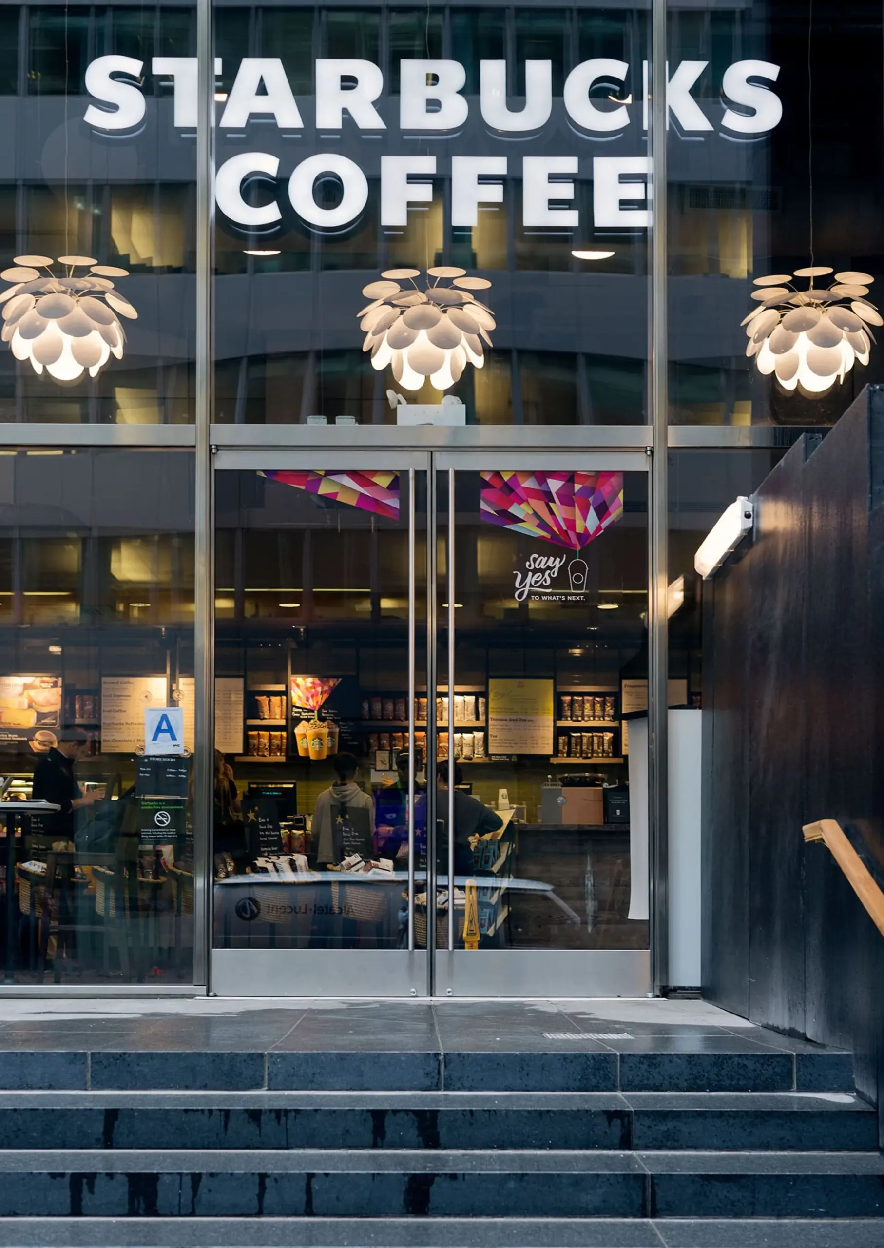 Drei weiße Marset Pendelleuchten Discocó über dem Eingang eines Cafés