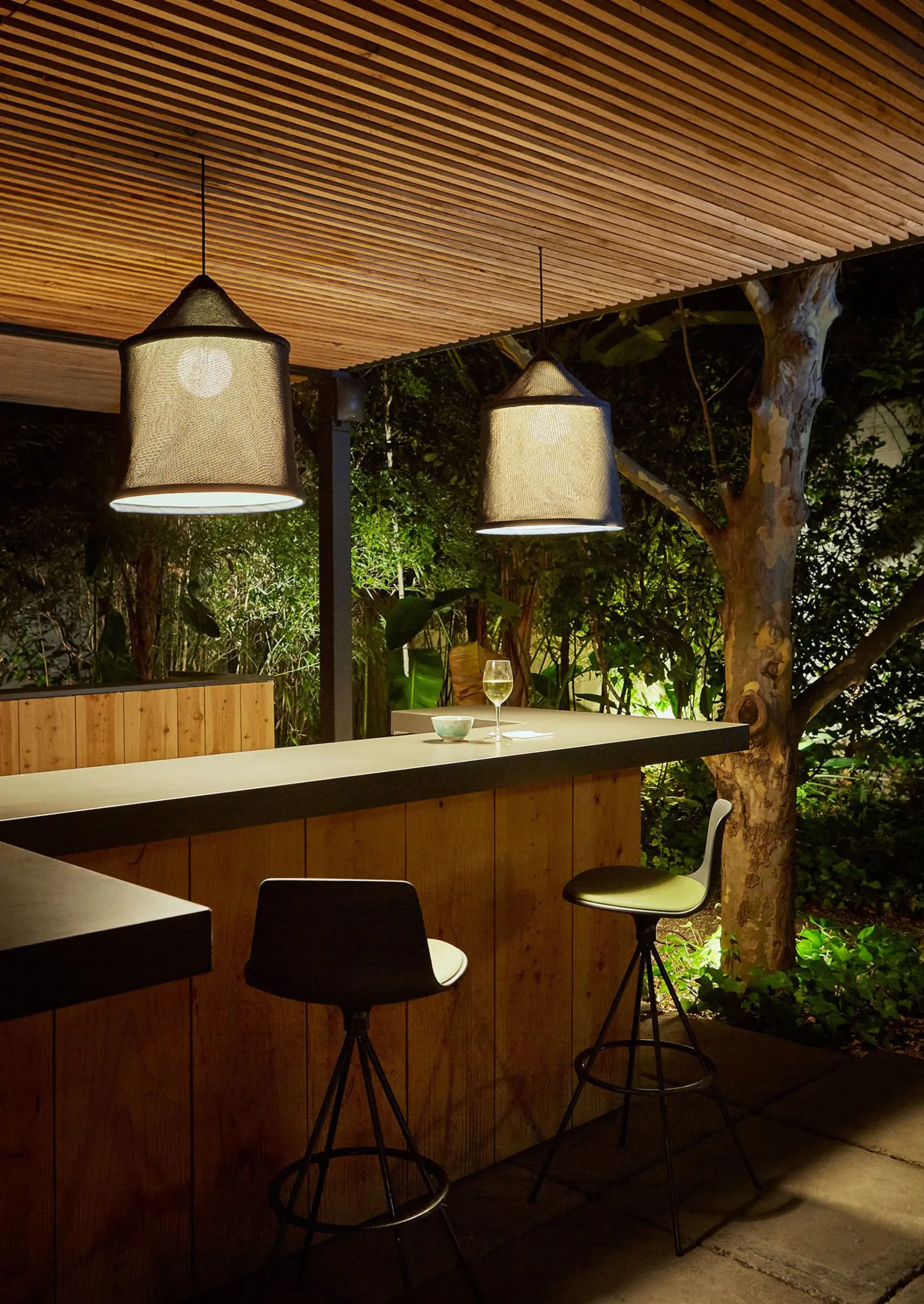 Zwei Marset Outdoor-Pendelleuchten Jaima über der Theke einer Gartenbar