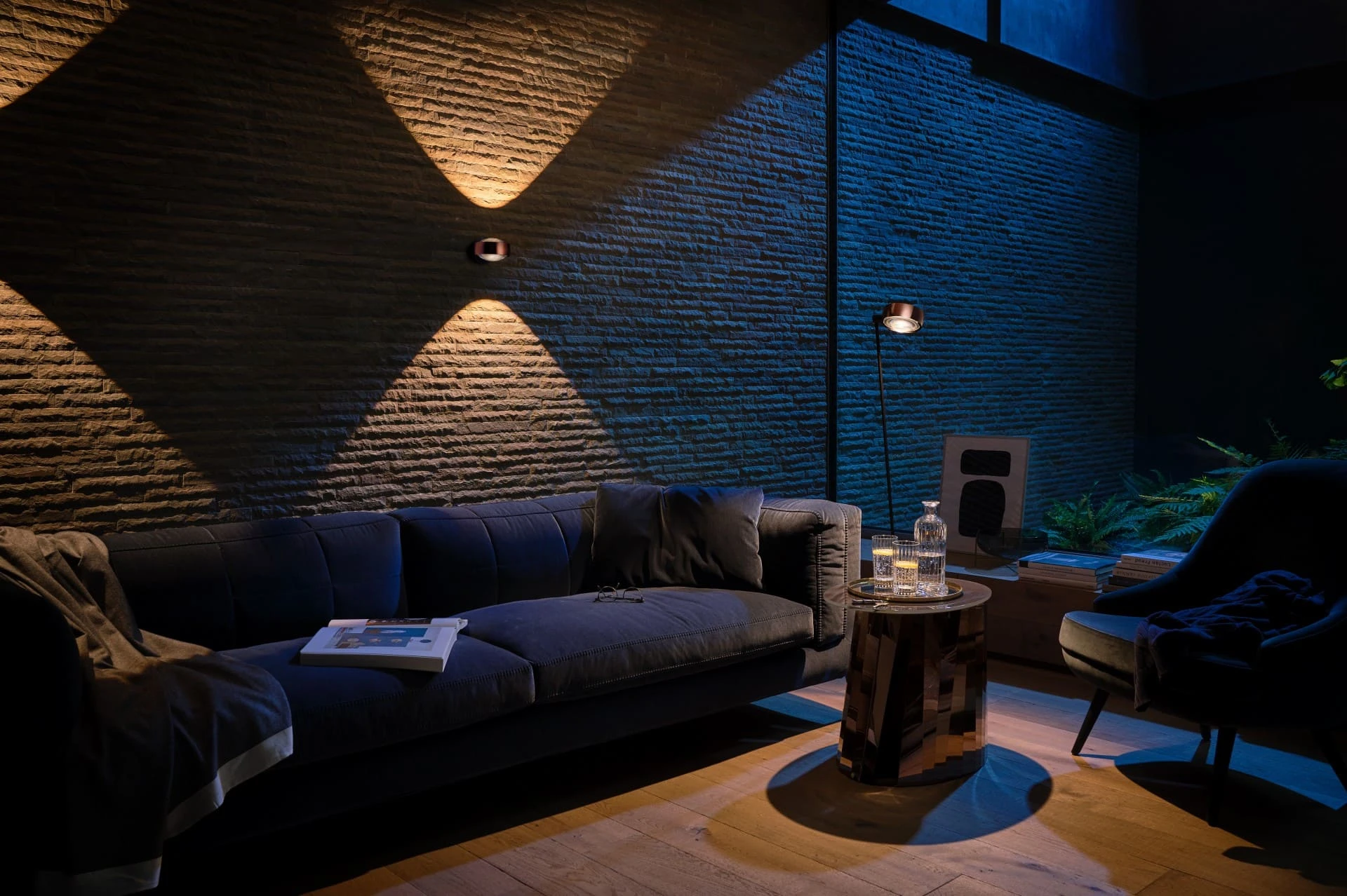 Occhio Wandleuchten Sento verticale werfen Lichtkegel auf die Natursteinwand im Wohnzimmer