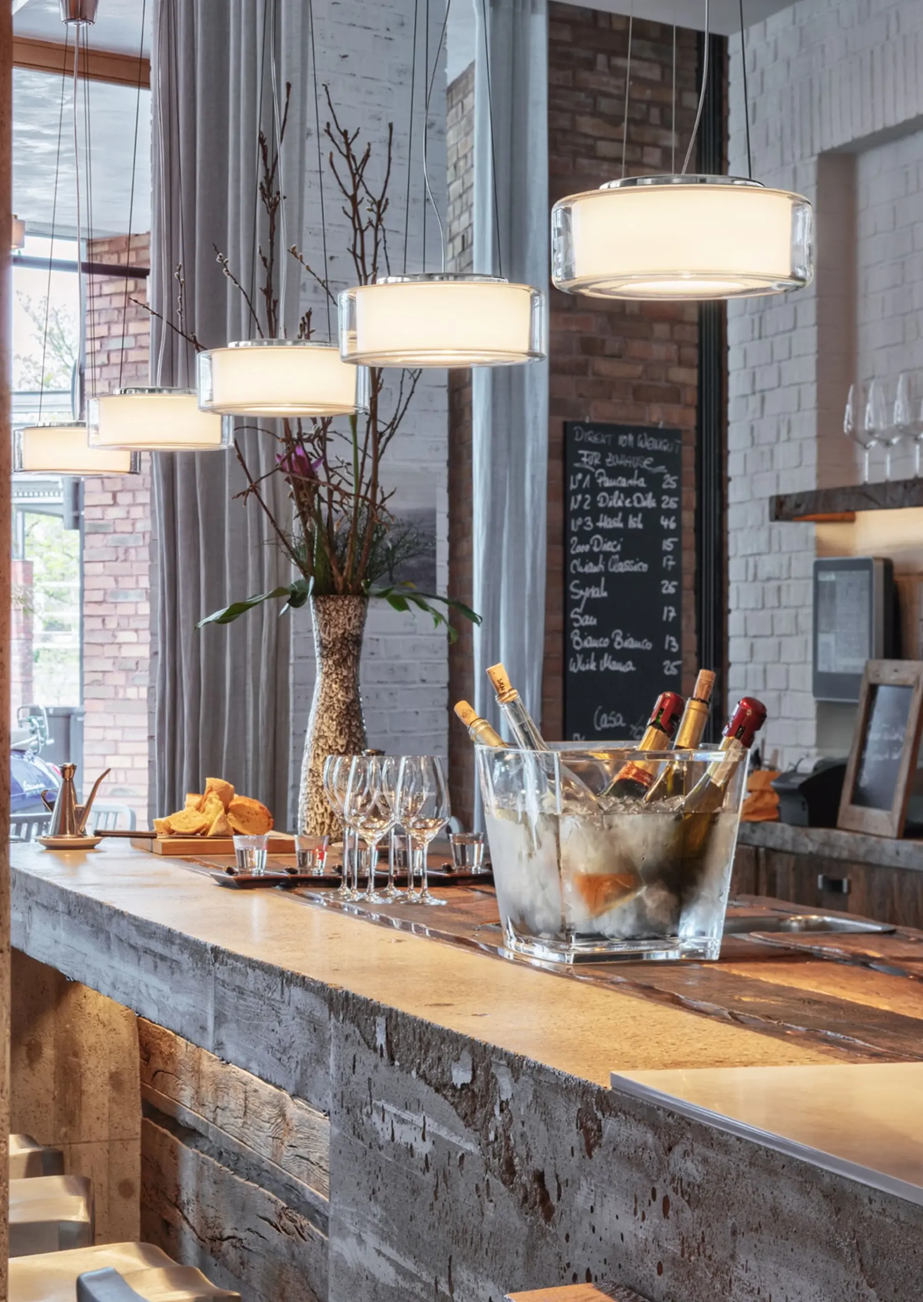 serien.lighting Pendelleuchten Curling aus klarem Glas über einer Bartheke