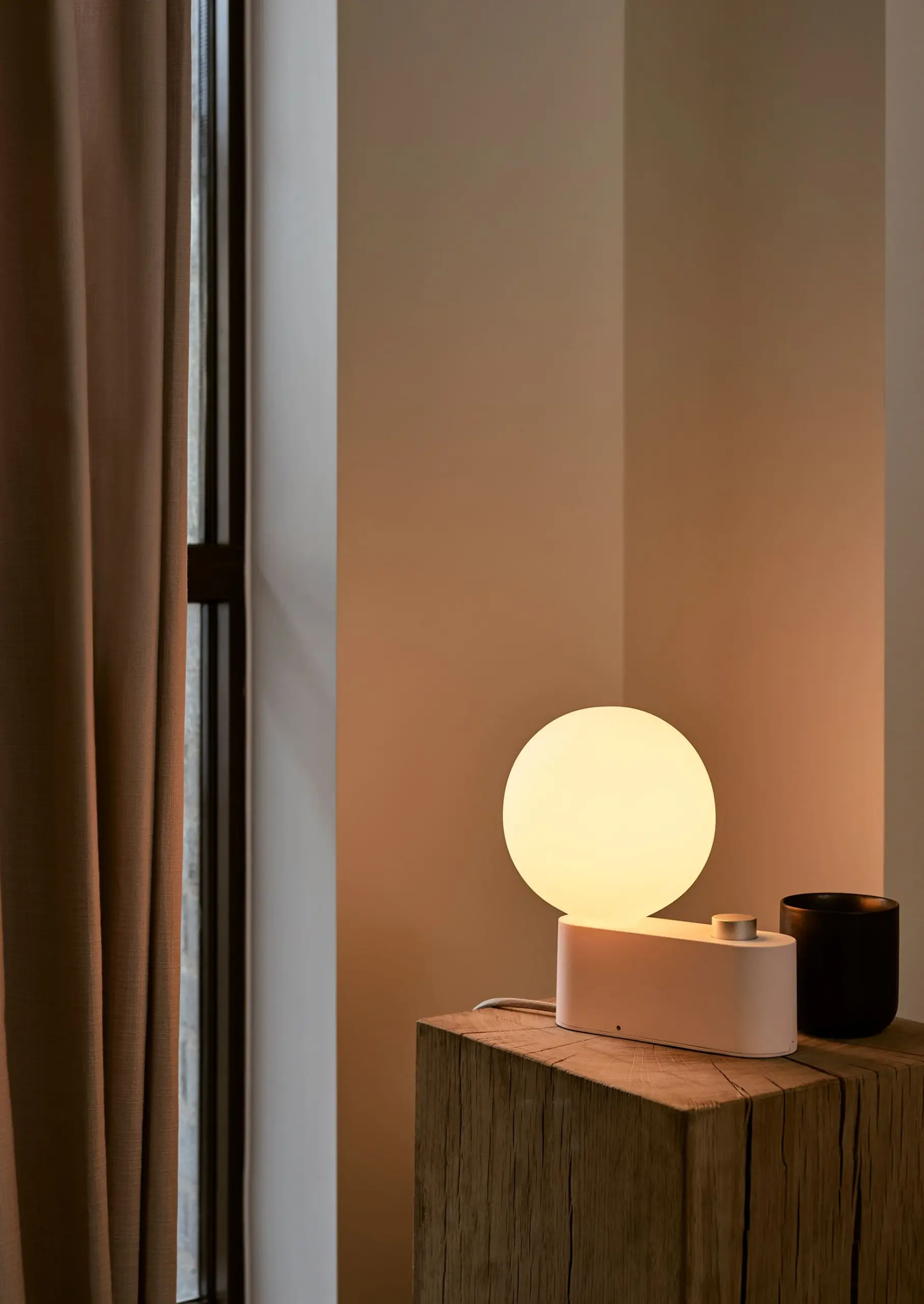 Tala Tischleuchte Alumina in Rosa mit Opalglaskugel auf einem Holzblock