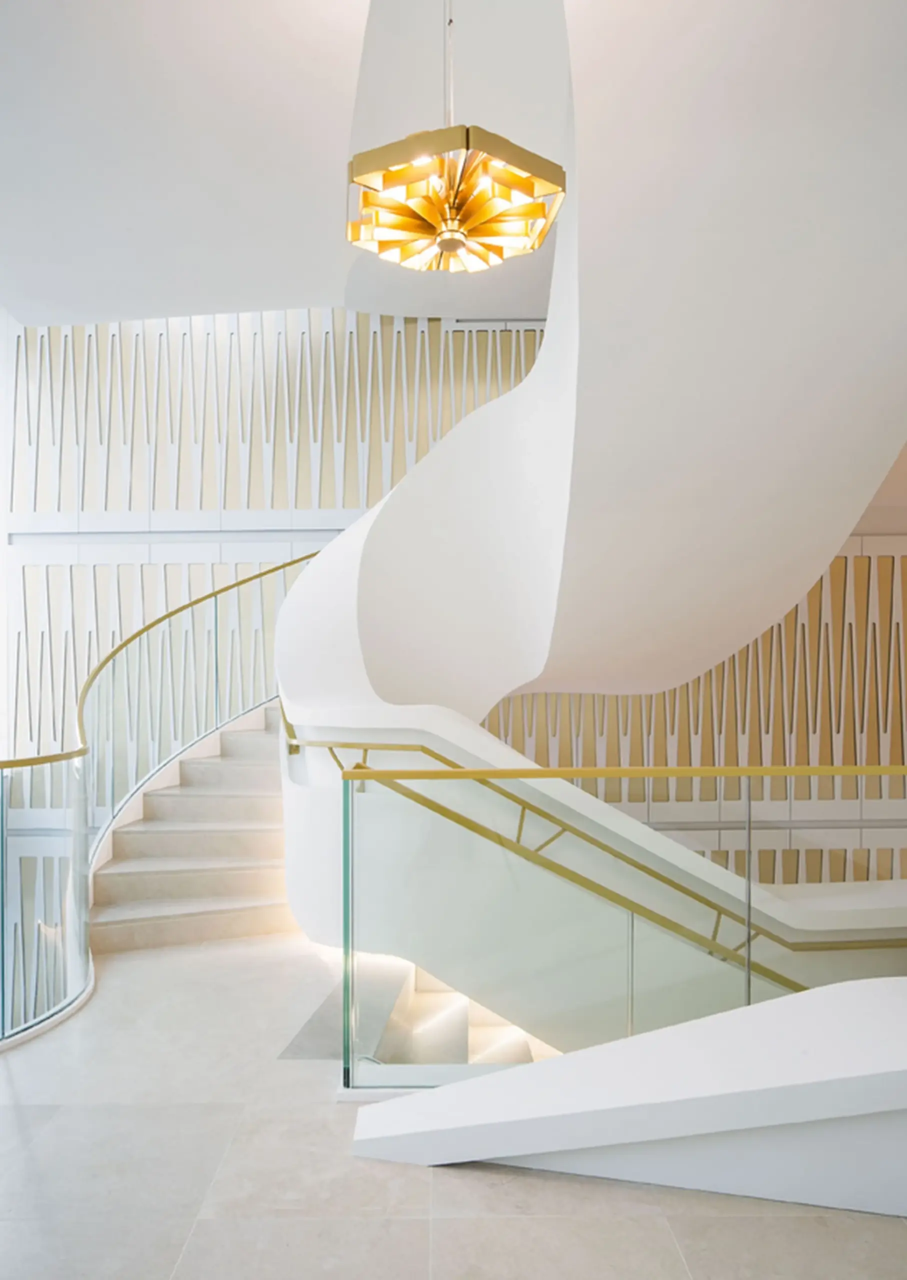 Goldene Wever & Ducré Pendelleuchte über einer weißen Wendeltreppe